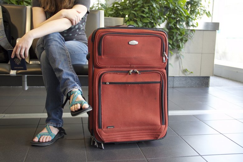 Jeune femme assise près d'une valise dans un aéroport